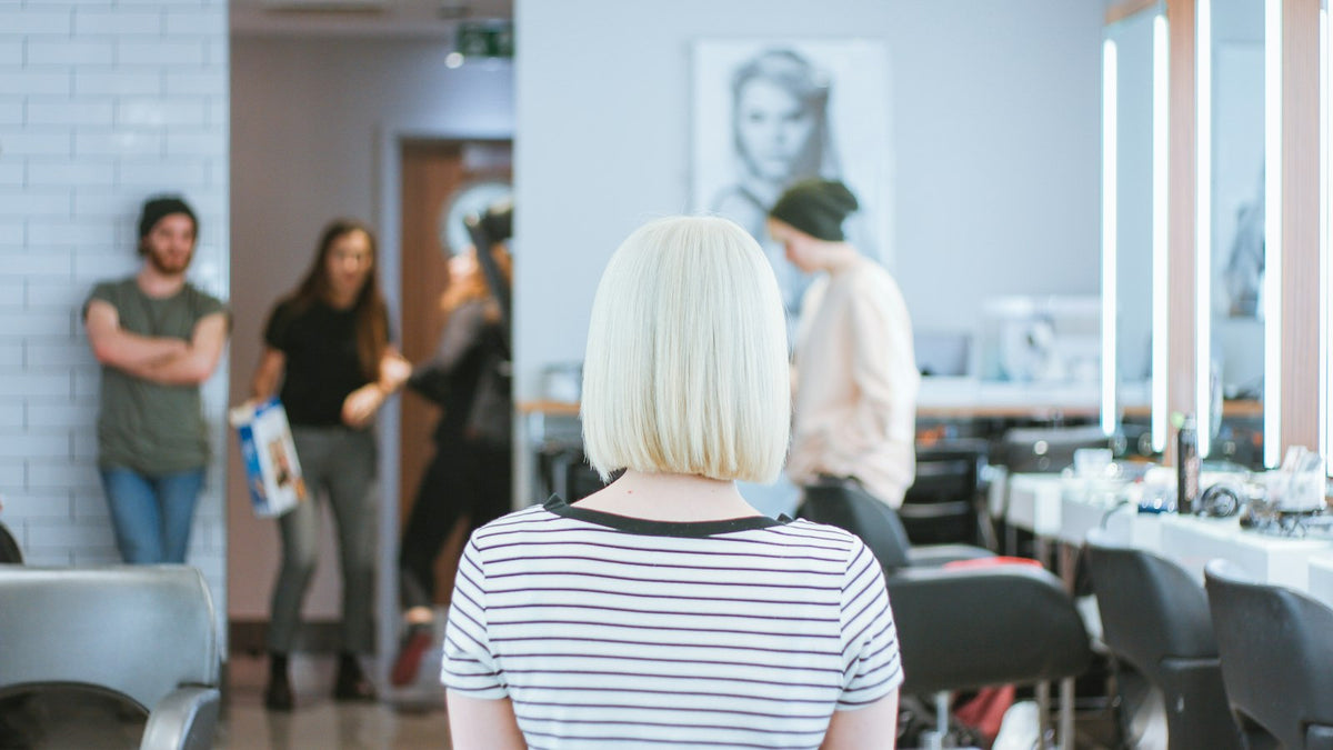 Frau mit langen blonden Haaren von hinten, heller Hintergrund