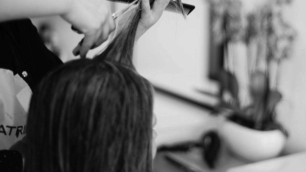 Friseurin schneidet die Haarspitzen einer Kundin im Salon