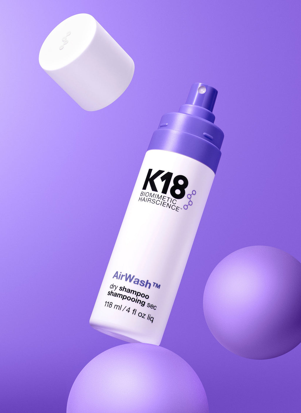 K18 AirWash Trockenshampoo Flasche im Stillleben mit lila Kugeln