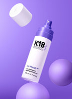 K18 AirWash Trockenshampoo Flasche im Stillleben mit lila Kugeln