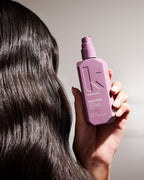 Hand hält die Kevin Murphy Night Shift Flasche vor geglättetem Haar