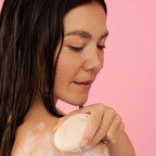 Foamie Feste Duschpflege Oat to Be Smooth – Anwendung: Frau seift die Schulter mit dem Duschstück ein