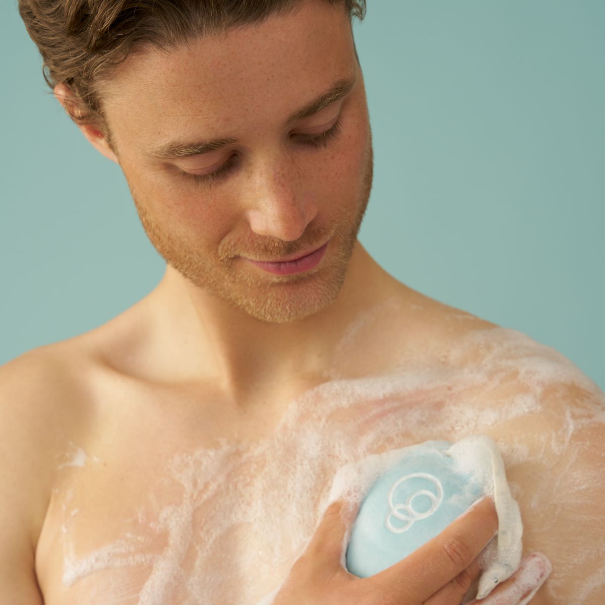 Foamie Men 3in1 Seas the Day – Anwendung: Mann seift den Oberkörper mit dem Duschstück ein