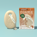 Foamie Feste Duschpflege Gingerbread Cookie 80 g: cremefarbenes Duschstück mit Kordel neben der Verpackung mit Lebkuchenmotiv