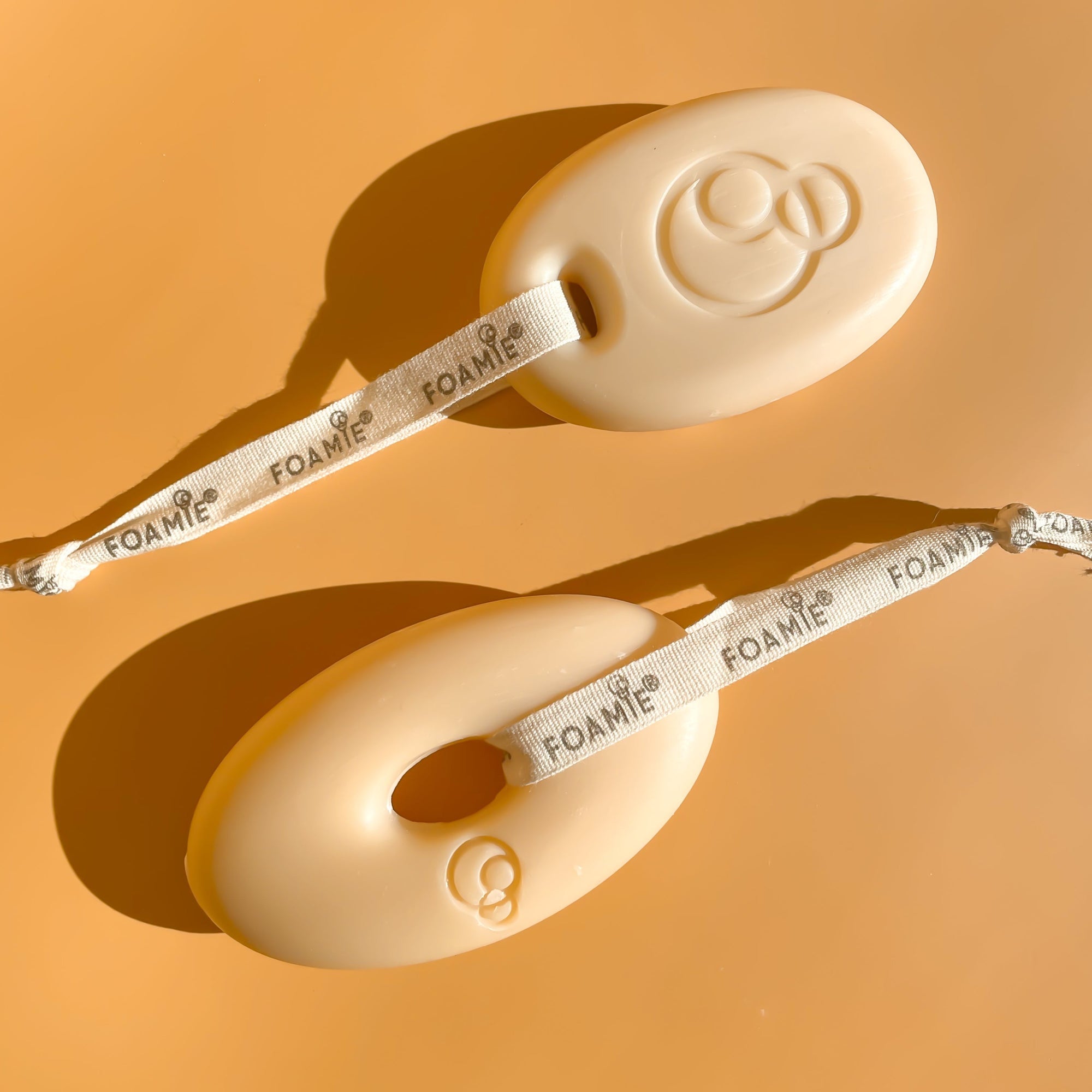 Foamie Feste Duschpflege Oat to Be Smooth – zwei Duschstücke vor orangem Hintergrund
