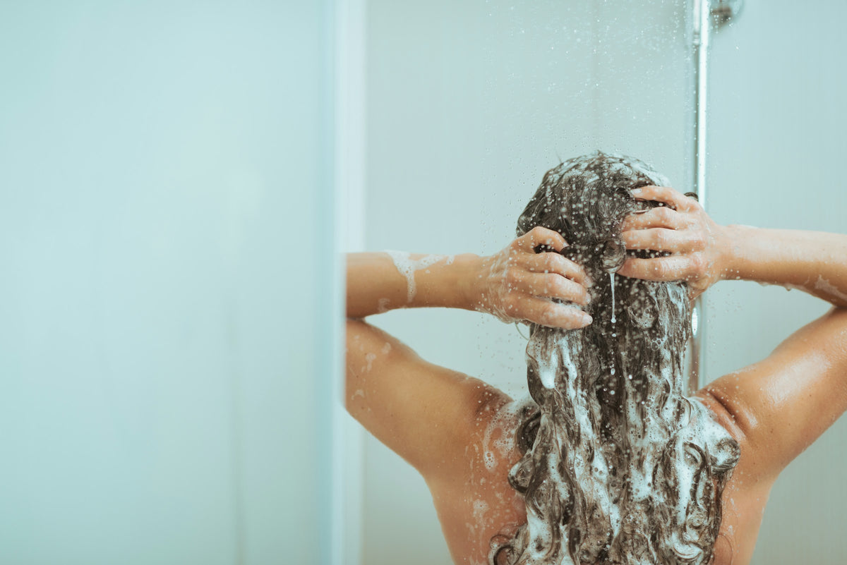 Conditioner: Frau wäscht ihre Haare unter der Dusche
