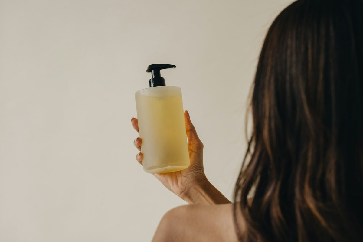 Sulfatfreies Shampoo: Frau hält eine Shampoo-Pumpflasche
