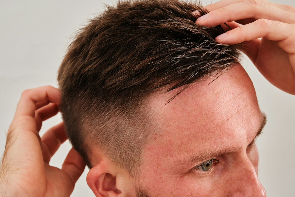 Haarwachs und Paste: Mann formt kurzes Haar mit den Fingern