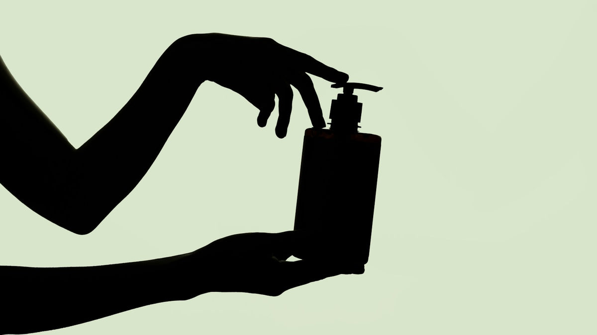 Hände drücken den Pumpspender einer großen Shampooflasche – Friseurbedarf in Vorratsgröße für zu Hause